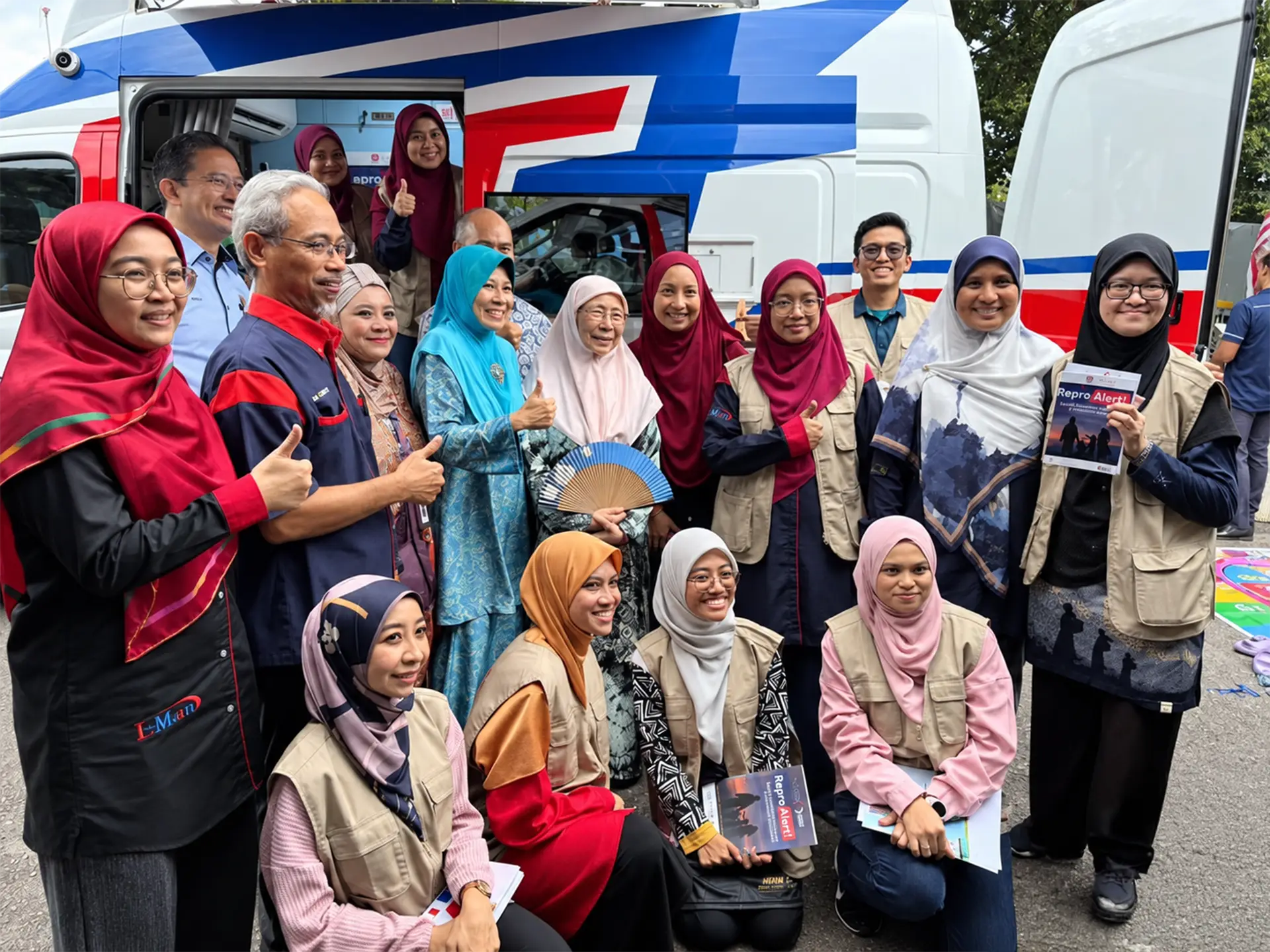 Community health partners and volunteers gathered beside a mobile health vehicle