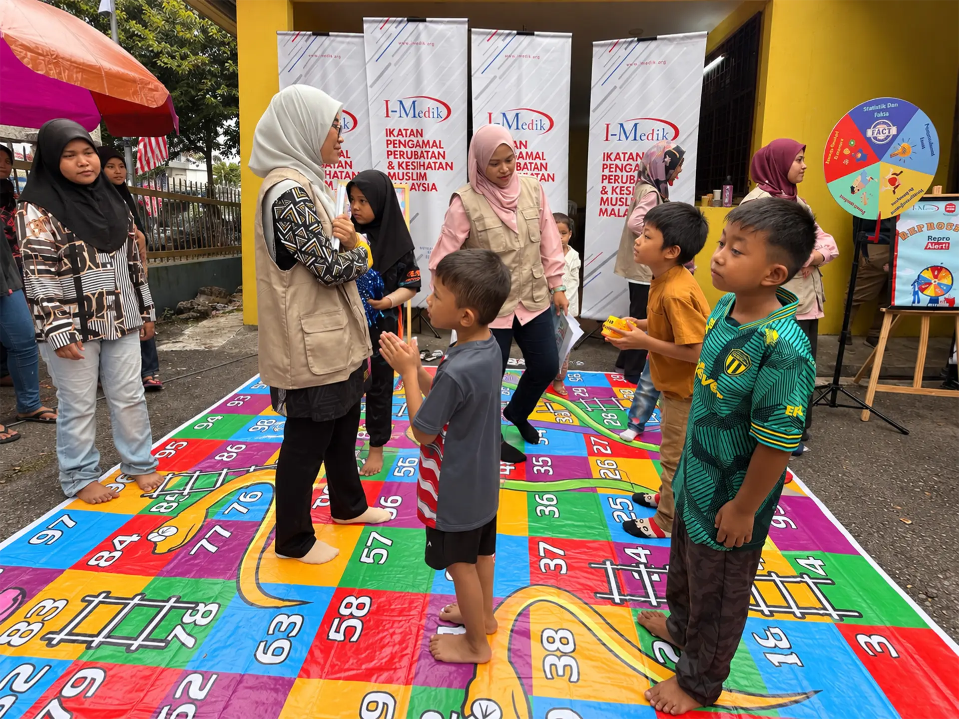Children and facilitators taking part in an outdoor activity on a colourful game mat