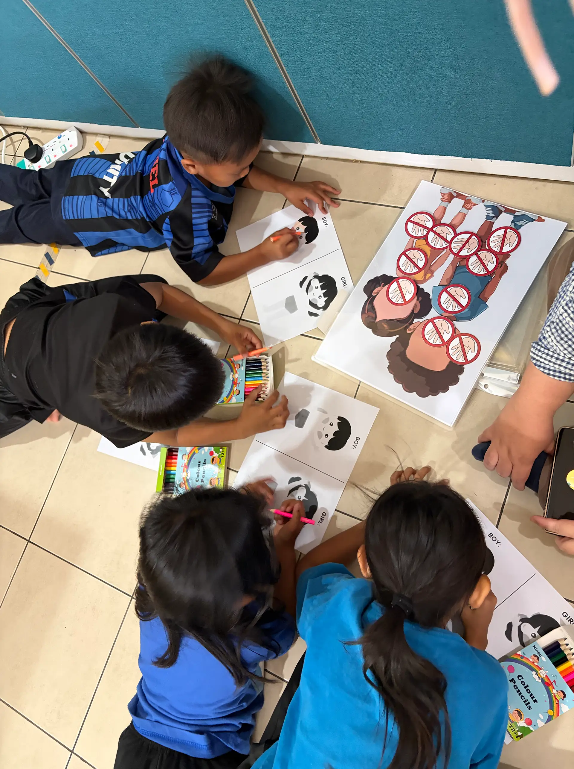 Children colouring activity sheets together on the floor