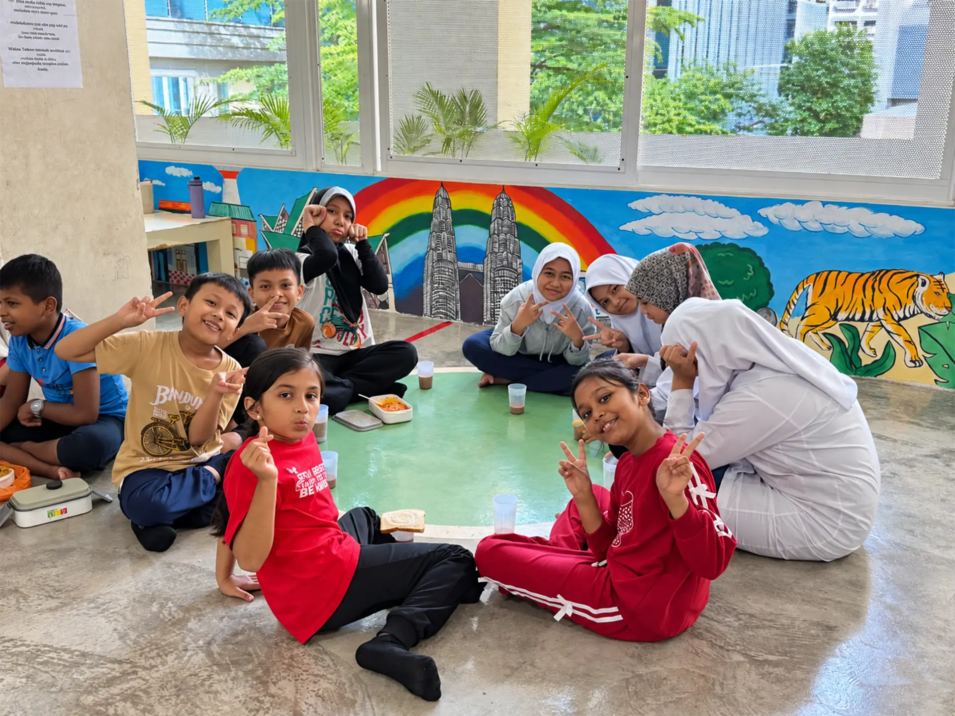 Children gathered together around a green table at Yayasan Chow Kit