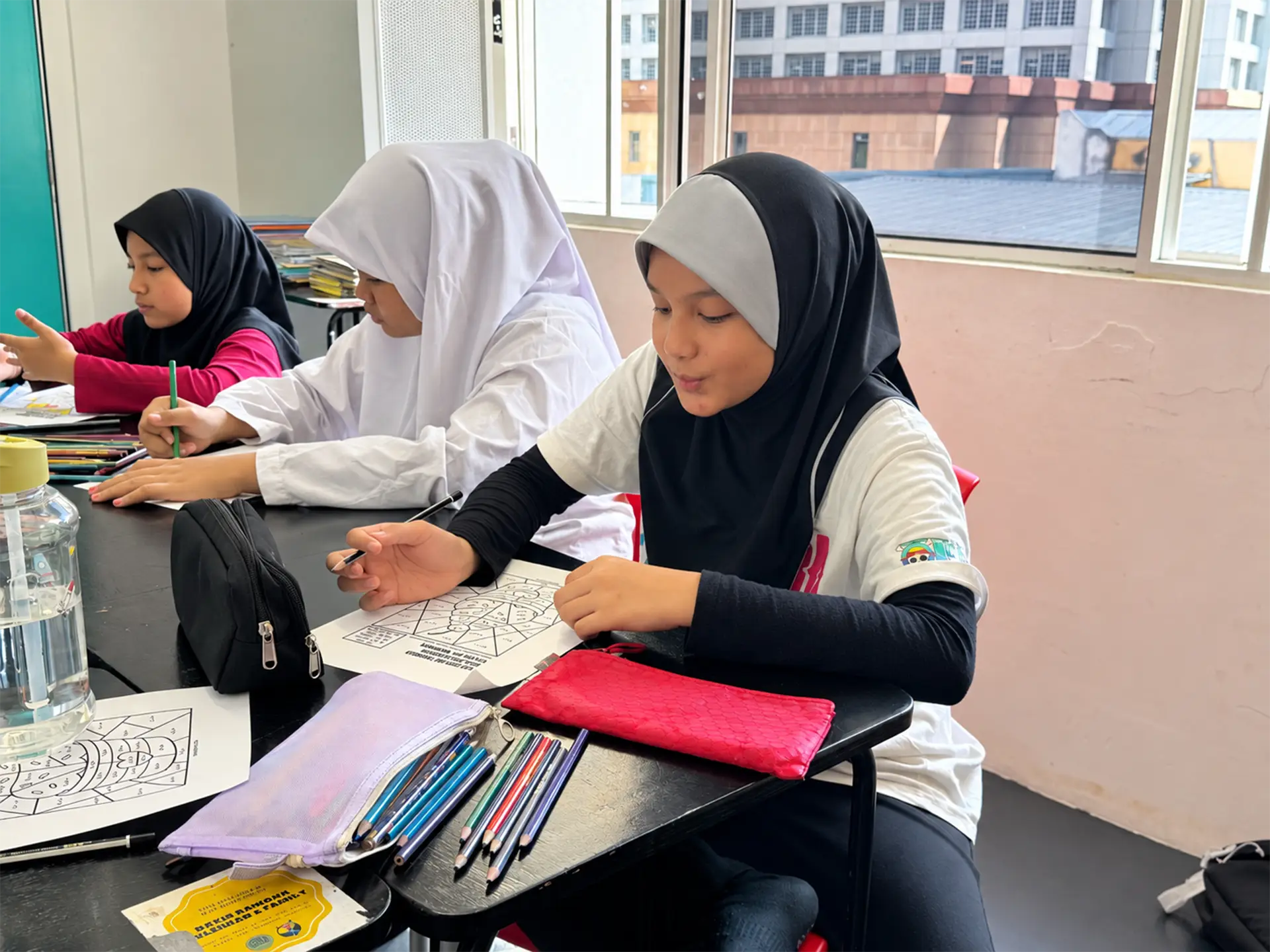 Children working on colouring activities at classroom desks