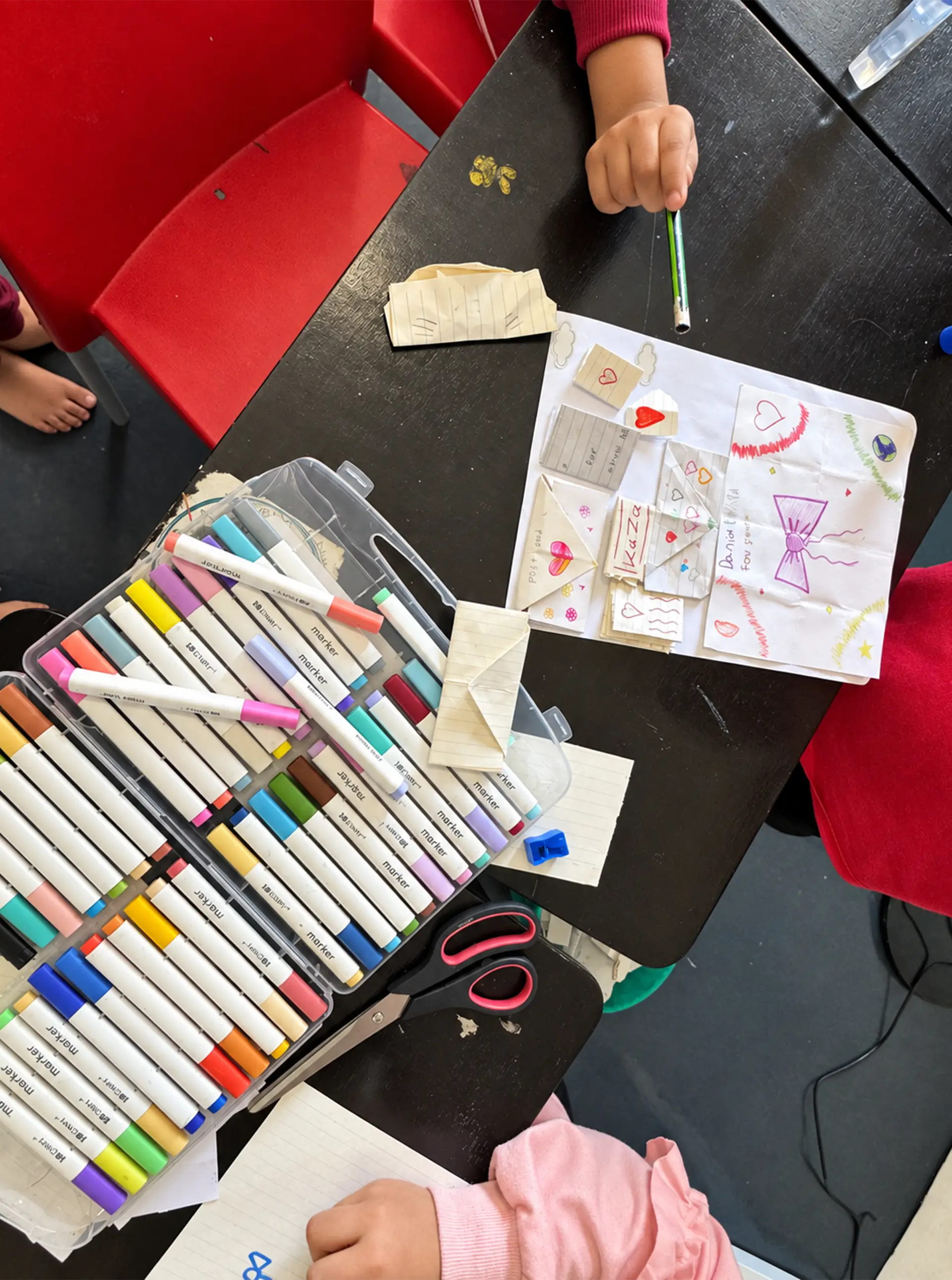 Colourful markers and handmade paper crafts on a classroom table