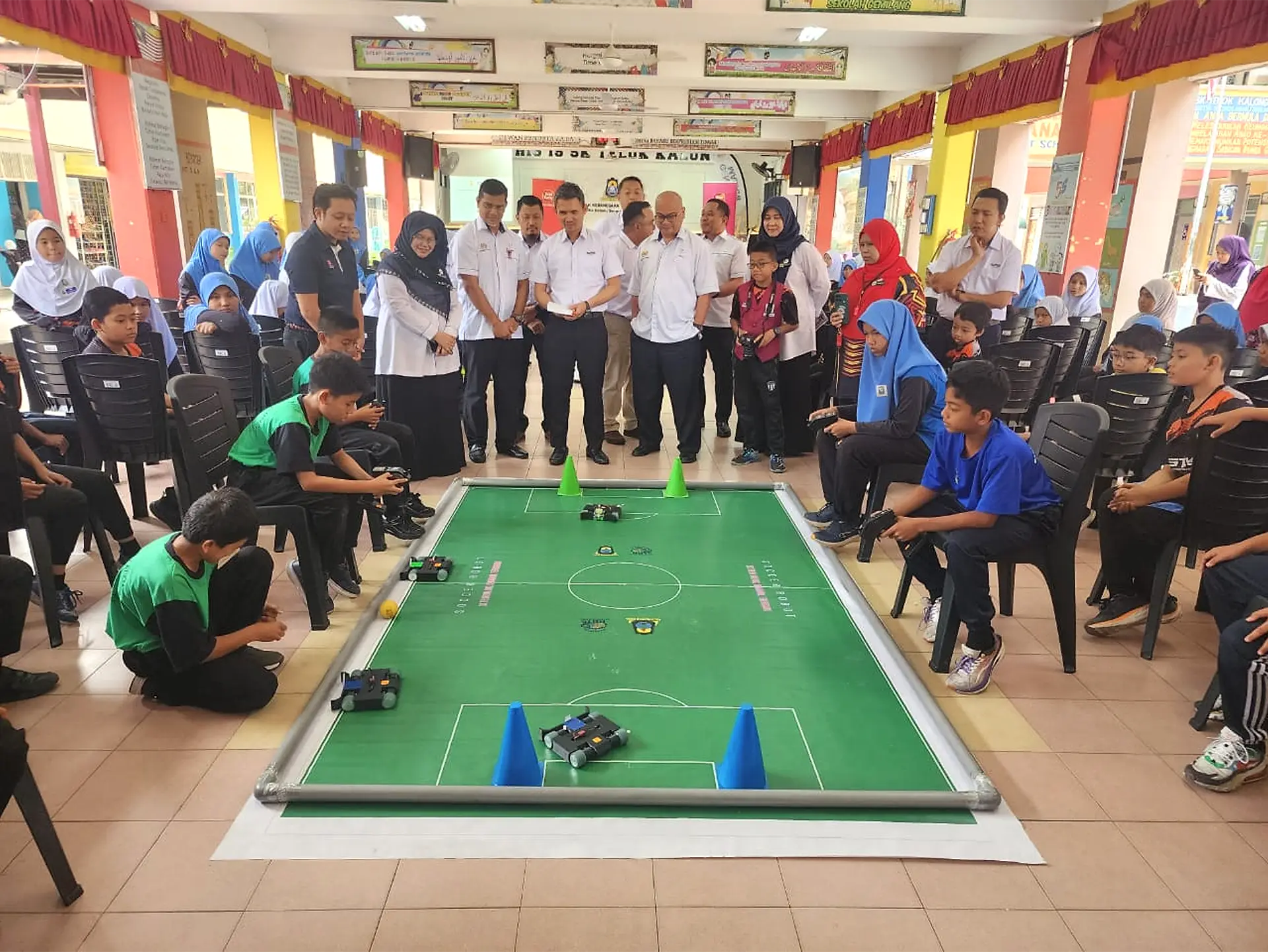 Students demonstrating robots on a miniature football pitch during a school visit