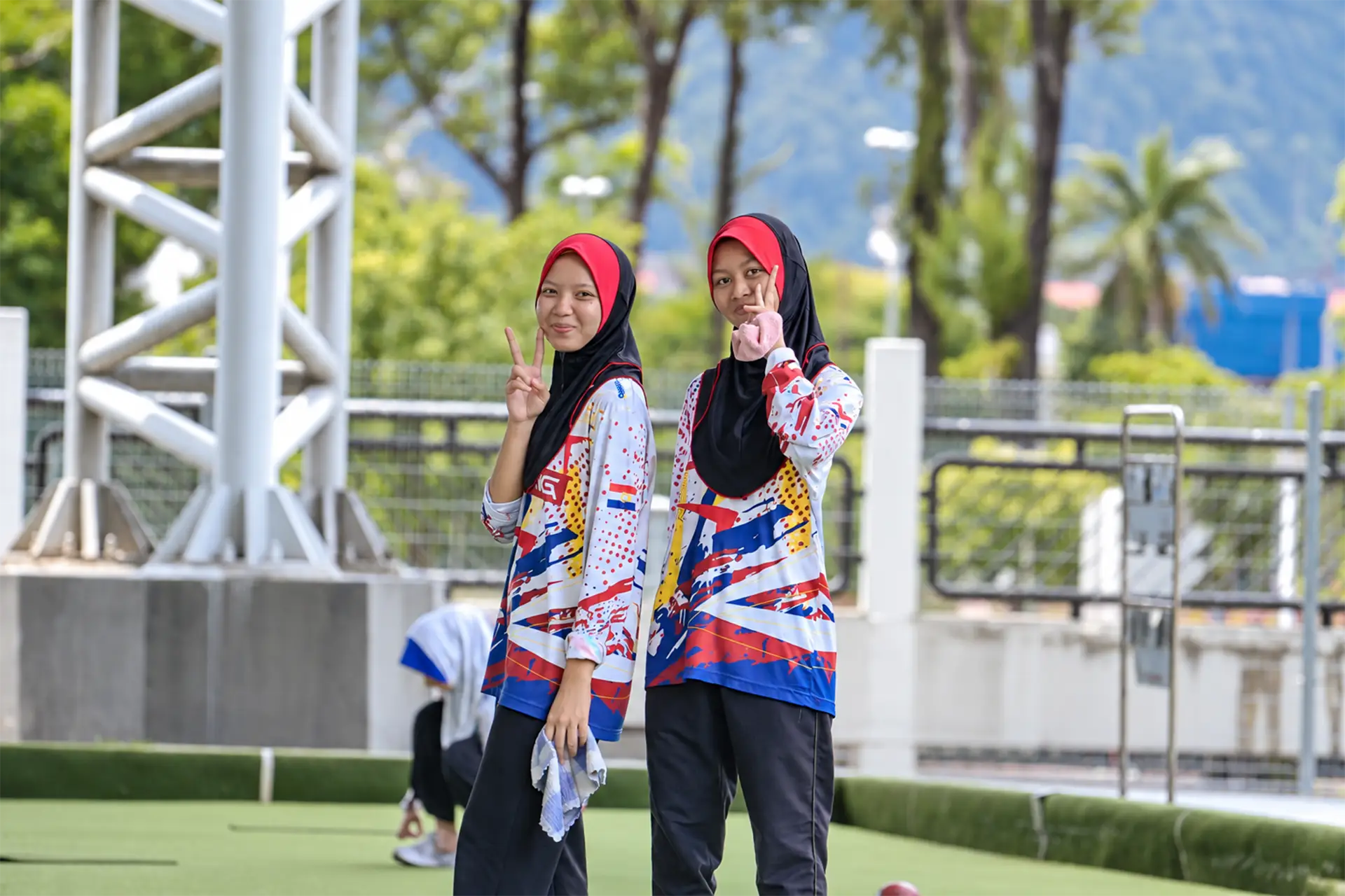 Two young lawn bowls players standing beside the green